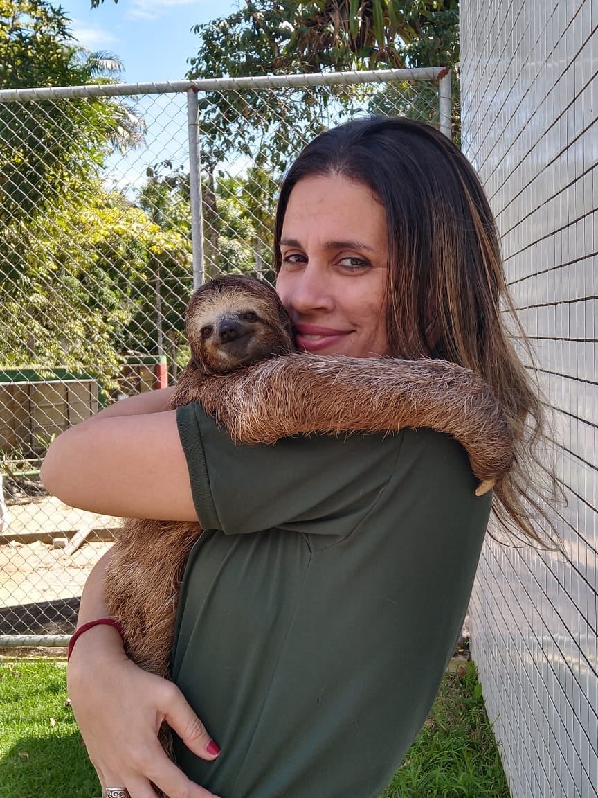 Dra. Caroline Fonseca segurando uma preguiça no colo, sorrindo